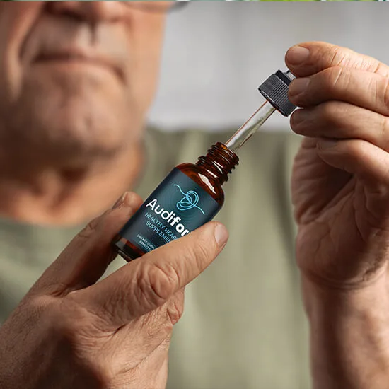 Mature adult holding an open bottle of Audifort with its liquid dropper